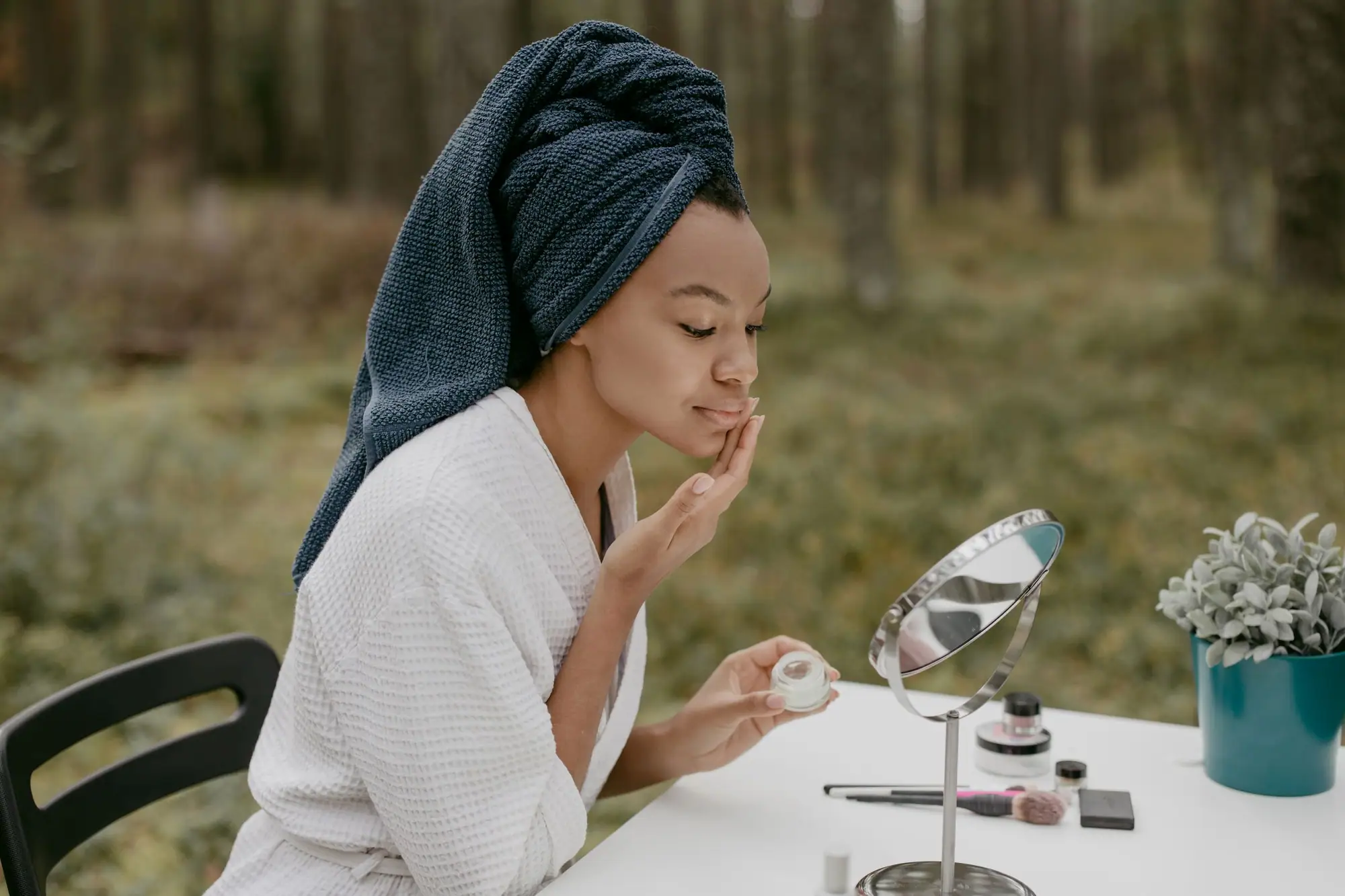 A woman applying moisturiser at a table outdoors